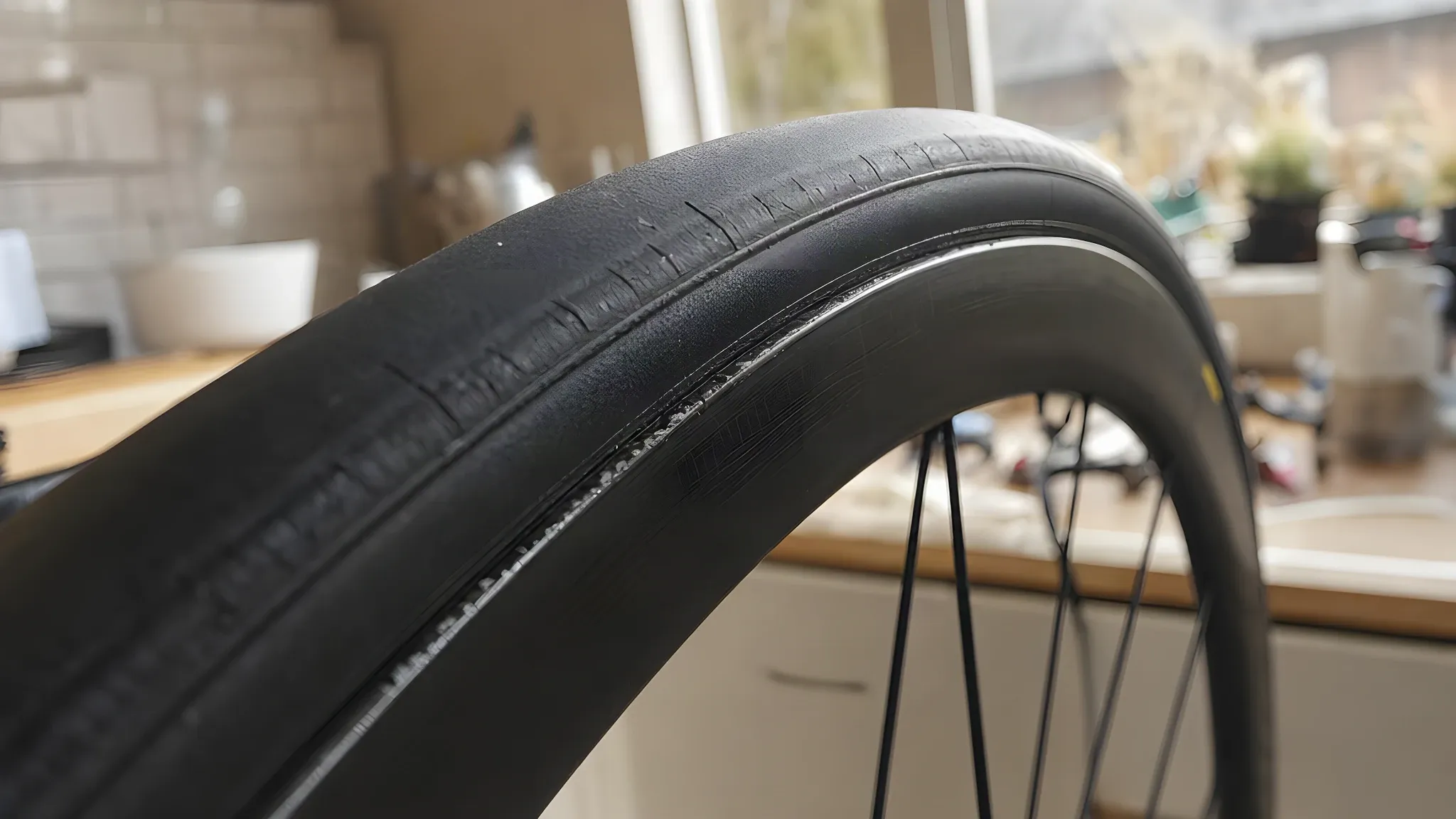 Close-up of an inflated tubeless road tyre on a black rim, the thin moulded bead line sitting an even distance above the rim edge all the way round the visible section