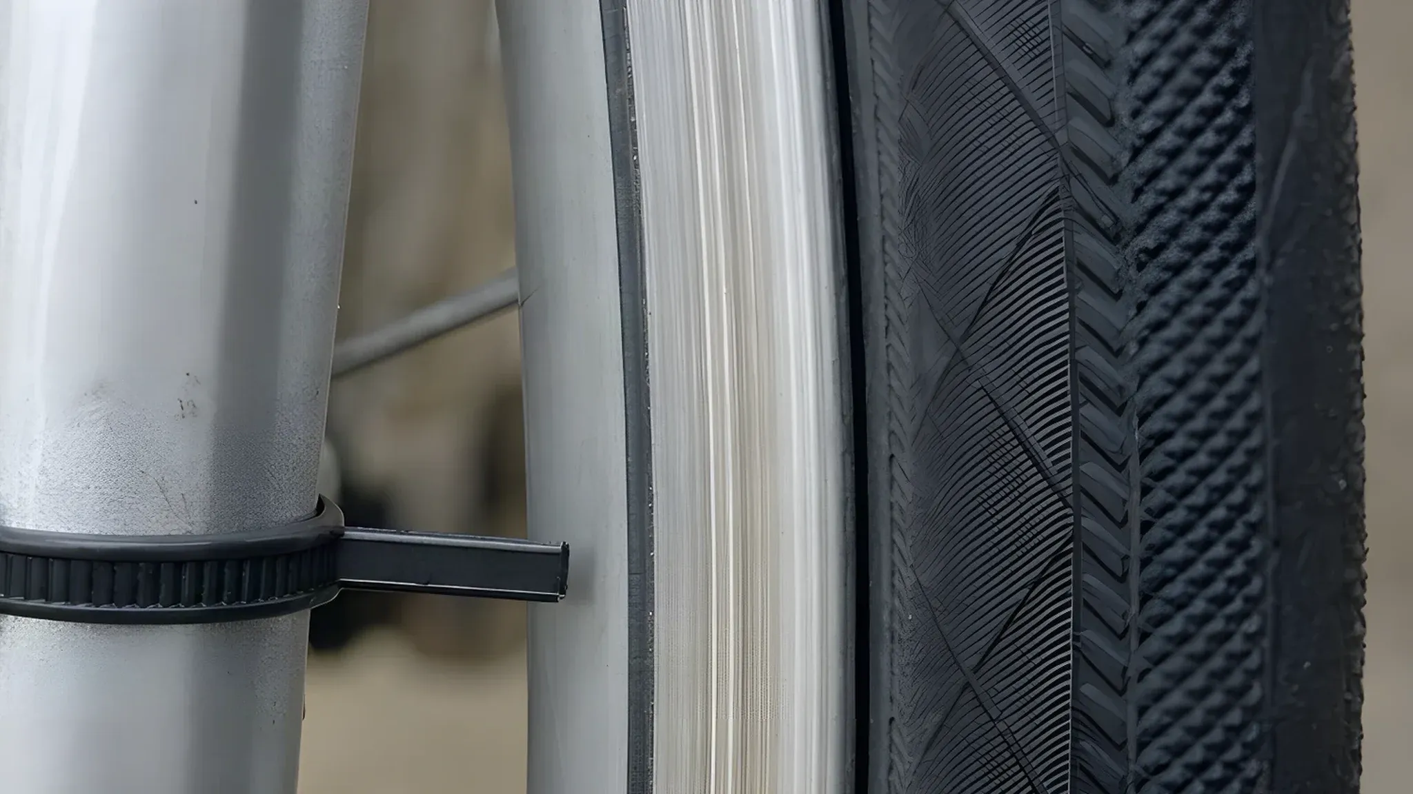 Close-up of a zip tie fastened round a fork blade, its cut tail stopping a couple of millimetres short of the side of the rim, used as a gauge for sideways wobble